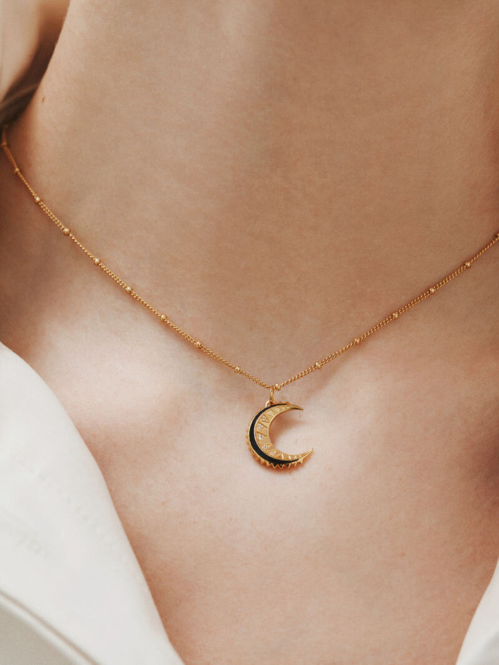 Charm de plata 925 bañada en oro amarillo de 18K con topacios blancos, esmalte negro y forma de luna